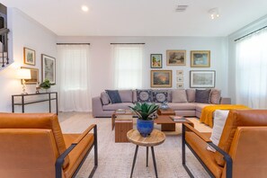 A modern living room with a sofa, two armchairs, a coffee table, and a side table with a lamp and plant. - Family Beach House near the Ocean (Melbourne Beach)