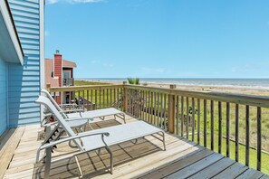 A wooden deck with two lounge chairs and a small building, overlooking a beach. - Remodeled Beachfront Home w/ 2 decks & stellar Gulf views - Steps from Beach (Galveston)
