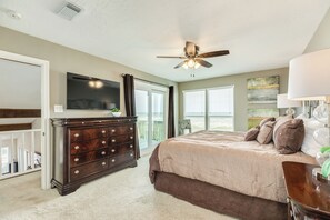 A bedroom with a bed, dresser, ceiling fan, TV, and large windows. - Remodeled Beachfront Home w/ 2 decks & stellar Gulf views - Steps from Beach (Galveston)