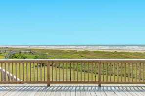 A wooden deck with a railing overlooking a beach.