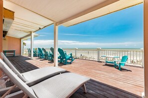 A covered deck with wicker lounge chairs and a view of the beach. - Comfortable Pet Friendly Beachfront Home - Great Sunrises from the Open Deck! (Galveston)