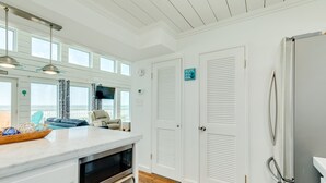 A kitchen with a marble countertop, a microwave, and a refrigerator. There are two white doors with louvered tops and a sign that reads "HOPE STUDENT SOUL". - Budget & Pet Friendly Beachfront Home - Great for Couples or Small Families (Galveston)