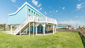 A two-story building with a white balcony and stairs leading to the upper level. - Budget & Pet Friendly Beachfront Home - Great for Couples or Small Families (Galveston)