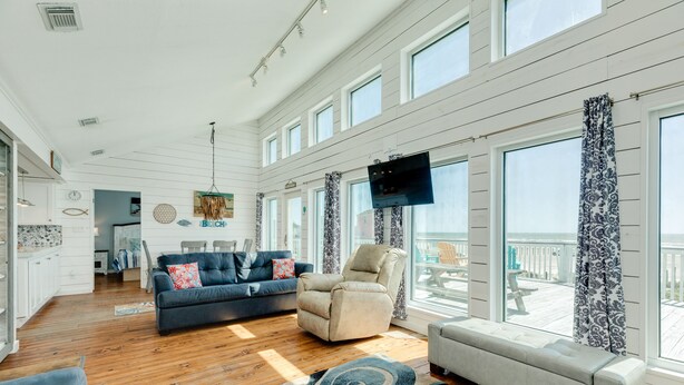 A spacious living area with a large window, a sofa, a chair, and a television. - Budget & Pet Friendly Beachfront Home - Great for Couples or Small Families (Galveston)