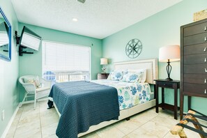 A bedroom with a bed, a chair, a nightstand, a lamp, and a wall clock. - Private Beachfront Home - HOT TUB w/ Gulf Views, Steps from Beach & Dog Friendly (Galveston)