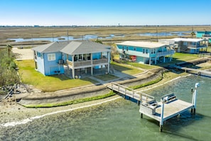 A coastal property with multiple buildings, a dock, and a clear view of the marshy landscape.