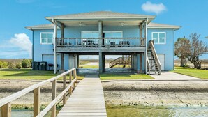 Una casa a due piani con un balcone, un molo e una scala che conduce a una zona coperta.