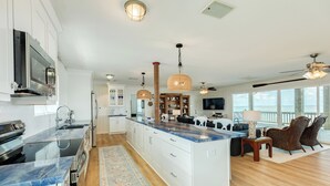 Un'ampia cucina con una grande isola, mobili bianchi e vista sull'area soggiorno.