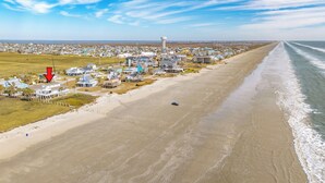 Une ville côtière dotée de propriétés en bord de mer, d’un phare et d’une plage.