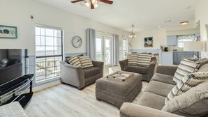 Ein geräumiges Wohnzimmer mit Deckenventilator, zwei Sofas, einem Couchtisch und einem Fernseher.
