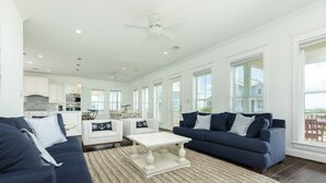 A spacious living room with a large white coffee table, two sofas, and a kitchen in the background. - Private Beachside Home w/ 4 Suites, Gulf Views, 2 Covered Decks & 200' to Beach (Galveston)