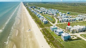An aerial view of a coastal residential area with beachfront properties, a golf course, and a clear sky. - Private Beachside Home w/ 4 Suites, Gulf Views, 2 Covered Decks & 200' to Beach (Galveston)