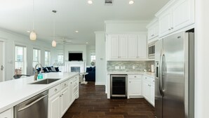 A spacious kitchen with white cabinetry, a stainless steel refrigerator, and a large island with a sink. - Private Beachside Home w/ 4 Suites, Gulf Views, 2 Covered Decks & 200' to Beach (Galveston)