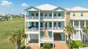 A multi-story beachfront property with balconies, a covered front porch, and a well-maintained lawn. - Private Beachside Home w/ 4 Suites, Gulf Views, 2 Covered Decks & 200' to Beach (Galveston)