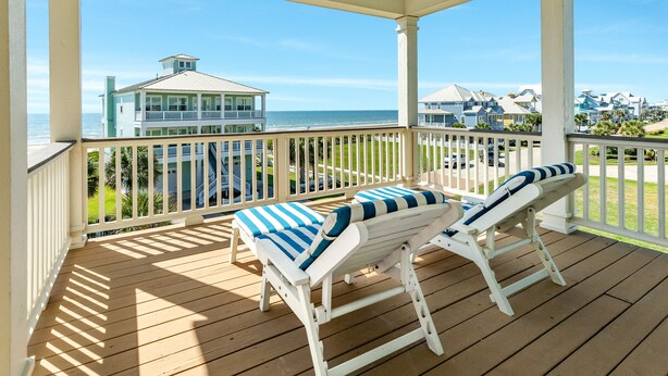 A wooden deck with two white lounge chairs and a table, overlooking a beach and ocean. - Private Beachside Home w/ 4 Suites, Gulf Views, 2 Covered Decks & 200' to Beach (Galveston)