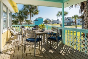 A wooden deck with a table and chairs, a covered seating area, and a view of the surrounding neighborhood. - Updated Beachside Home w/ Fully Equipped Kitchen, Large Deck+Patio, Dog Friendly (Galveston)