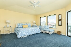 Ein Schlafzimmer mit Bett, Sitzbank, Deckenventilator und Blick durch ein Fenster.