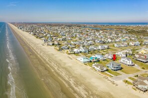 Ein Luftbild eines Küstenwohngebiets mit Häusern direkt am Strand und freiem Blick auf den Ozean.