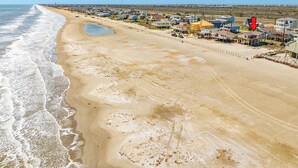 A coastal area with a sandy beach and houses along the shore. - Panoramic View Beachfront Home - Easy Beach Access, Outside Shower, Dog Friendly (Galveston)