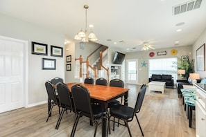 A spacious dining area with a wooden table and chairs, a staircase leading to another level, and a living area with a sofa and coffee table.