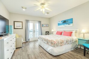 A bedroom with a bed, a television, a desk, and a window with curtains.