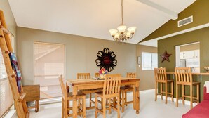 A dining area with a wooden table and chairs, a chandelier, and a decorative wall piece. - Single Level Beachside Home, Great for Families & Dog Friendly - Walk to Beach (Galveston)