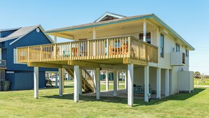 A two-story house with a wooden deck and a covered porch. - Single Level Beachside Home, Great for Families & Dog Friendly - Walk to Beach (Galveston)
