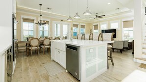 Una cocina amplia con una isla central, sillas de madera y lavavajillas.