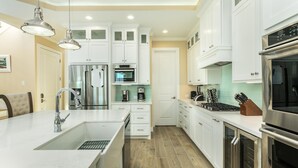Una cocina moderna con gabinetes blancos, electrodomésticos de acero inoxidable y una isla grande con un lavamanos.