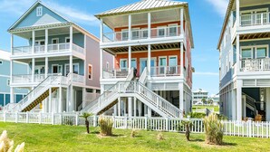 Una propiedad frente a la playa con varios balcones y una valla de piquete blanca.