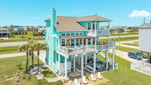 A two-story house with a balcony, outdoor seating, and a small deck. - Beachfront Pet Friendly Home w/ HOT TUB, Fenced Yard - Steps from Gulf & Beach (Galveston)