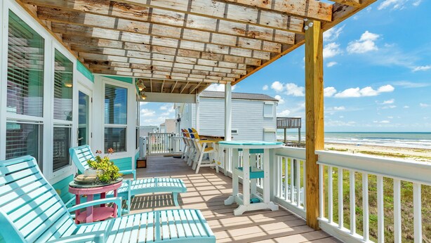 A covered porch with blue chairs and a table, overlooking a beach. - Beachfront Pet Friendly Home w/ HOT TUB, Fenced Yard - Steps from Gulf & Beach (Galveston)