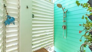 A turquoise exterior wall with a showerhead and a blue fish decoration. - Beachfront Pet Friendly Home w/ HOT TUB, Fenced Yard - Steps from Gulf & Beach (Galveston)
