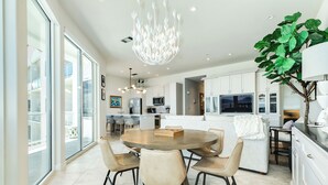 Una cucina moderna con isola centrale, ampie finestre e un lampadario.