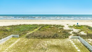 Uma praia com uma cerca branca e um contentor de lixo azul.