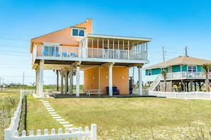 Ein zweistöckiges Haus mit Balkon, überdachter Veranda und kleiner Terrasse.
