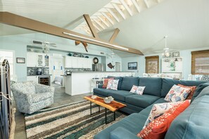 Ein geräumiges Wohnzimmer mit einem großen Ecksofa, einem Holztisch und einem Streifen Teppich.