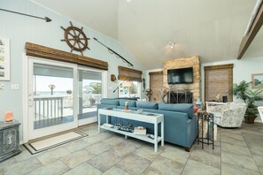 Un salon avec un canapé bleu, une table basse blanche, une cheminée et un téléviseur fixé au mur en briques.