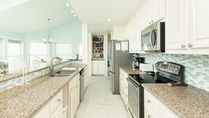 A kitchen with white cabinets, granite countertops, a refrigerator, microwave, stove, and a dishwasher.