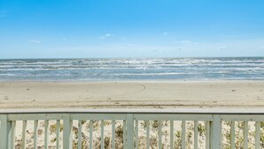 A beach with a wooden railing in the foreground.