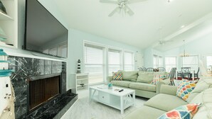 A living room with a fireplace, a sofa set, a coffee table, and a TV mounted on the wall.
