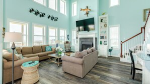 A spacious living room with a fireplace, a television, and a staircase.