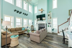 A spacious living room with a fireplace, a television, and a staircase.