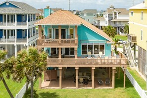 A two-story house with a balcony, a covered patio, and a fenced yard. - Beachfront Beauty w/ 2 Decks, No Bunk Beds, Open Plan & 220V NEMA 14-50 Charger (Galveston)