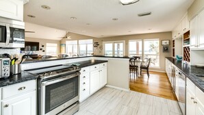 A spacious kitchen with white cabinets, a large island, and a dining area with a view. - Beachfront Beauty w/ 2 Decks, No Bunk Beds, Open Plan & 220V NEMA 14-50 Charger (Galveston)
