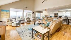 A spacious living area with a high ceiling, multiple seating options, and a view of the city. - Beachfront Beauty w/ 2 Decks, No Bunk Beds, Open Plan & 220V NEMA 14-50 Charger (Galveston)