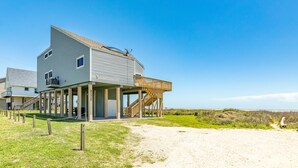 Una casa sul lungomare con una terrazza in legno e una scala che conduce a un piano superiore.
