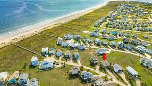 An aerial view of a coastal residential area with houses, a beach, and a boardwalk. - Cozy Beachside Home - Pet Friendly, Fenced Yard, Covered Deck, 0.5 blk to Beach (Galveston)