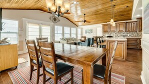 Une cuisine spacieuse dotée de meubles en bois, d’un grand îlot central et d’un coin repas avec une table et des chaises en bois.
