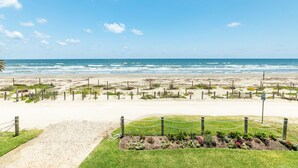 Vista de la playa con un área cercada, un sendero de tierra y un letrero que indica un límite de velocidad de 32 kilómetros por hora.